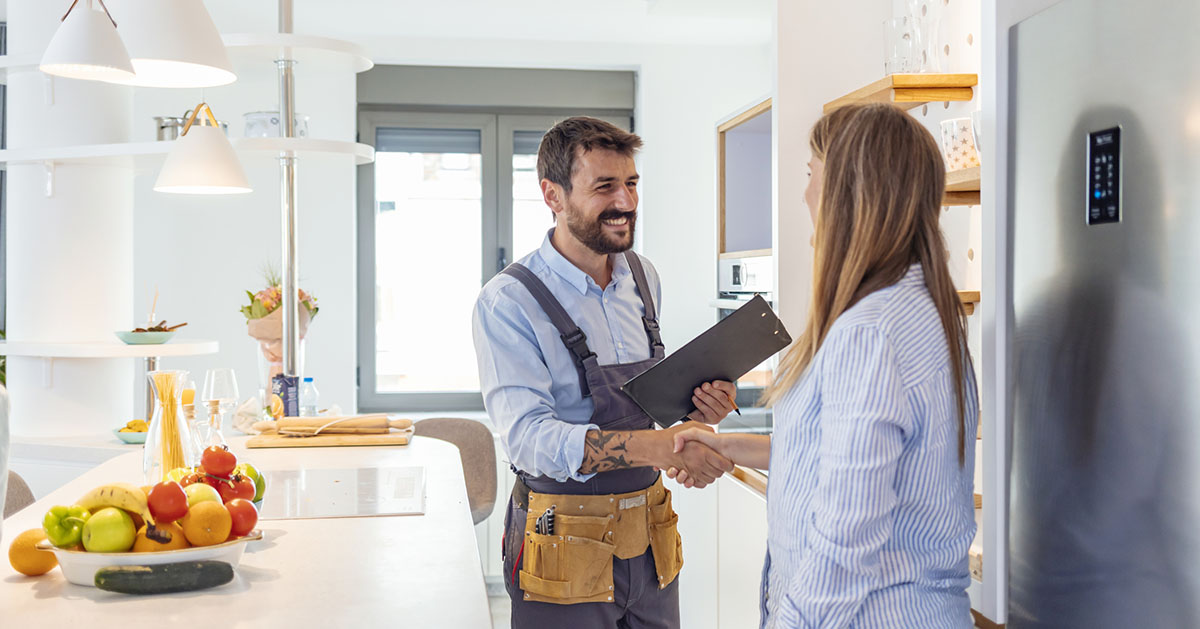 A woman in her kitchen shakes hands with a contractor