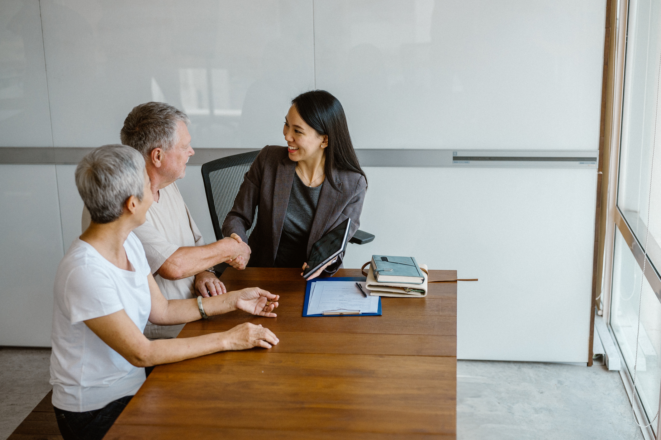 An older couple signs documents with their attorney